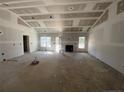 Spacious living room featuring a fireplace, ample natural light, and unfinished drywall, ready for customization at 84 Peach Orchard (Lot 4) Ln, Lillington, NC 27546