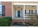 The inviting front porch has a blue front door, brick steps and white pillars at 59 Claymore Ct, Broadway, NC 27505