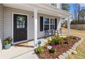 A welcoming covered front porch includes outdoor seating and a beautifully landscaped garden at 15 Summerwood Ln, Lillington, NC 27546