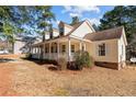 Side view of the home highlighting the expansive front porch with white columns and wooded surroundings at 281 Pineridge Cv, Sanford, NC 27332