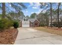 Inviting home with a brick and vinyl exterior, attached garage, long driveway, and landscaping against a wooded backdrop at 33 Woodbury Ln, Sanford, NC 27332