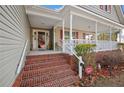 Inviting front porch with brick steps and white railings leading to the entrance of this cozy home at 15 Clearwater Hbr, Sanford, NC 27332