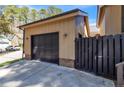 View of the garage attached to the home with a black door and a black wooden fence at 306 Harbor Trace, Sanford, NC 27332