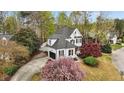 A lovely, elevated exterior shot displaying the home's manicured lawn, curved drive, and black garage door at 1300 Linden Ridge Dr, Holly Springs, NC 27540
