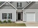 Close up of the home's front exterior featuring gray siding, black shutters and a two car garage at 405 Turriff Way, Cameron, NC 28326