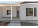 Inviting front porch with white pillars, a dark front door, and black shutters on a gray home at 4983 Ray Rd, Spring Lake, NC 28390