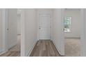 Bright hallway with hardwood floors and a white door, leading to carpeted rooms and a window view at 4983 Ray Rd, Spring Lake, NC 28390