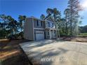 Well-maintained two-story home with gray siding, one-car garage, and a long concrete driveway at 205 Regis Ln, Coats, NC 27521