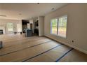Unfinished living room with large windows providing natural light, a fireplace, and view to the kitchen at 205 Regis Ln, Coats, NC 27521