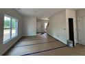 Unfinished open living space with large windows, neutral walls, and a staircase leading to the upper level at 205 Regis Ln, Coats, NC 27521