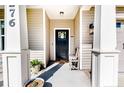 Welcoming front porch with wooden rocking chair, potted plants, and dark-stained front door at 276 Widgeon Way, Lillington, NC 27546