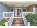 Inviting front porch with brick steps, white railings, and ceiling fans, creating a cozy entrance at 6138 St Andrews Dr, Sanford, NC 27332
