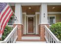 Inviting covered front porch with brick columns, and wood ceiling that lead to an elegant wood front door at 85 Heatherspring Way, Spring Lake, NC 28390