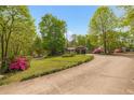 View of the home featuring a circular drive surrounded by lush trees and colorful plants at 9301 Nc 27, Lillington, NC 27546
