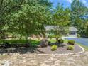 Landscaped front yard with mature trees and shrubbery, framing a charming single-story brick home at 6044 Saint Andrews Dr, Sanford, NC 27332
