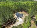 Expansive aerial view of a modern home surrounded by lush forest, a private driveway, and well-manicured landscaping at 716 Wildlife Rd, Sanford, NC 27332