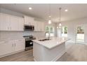 Bright kitchen featuring a center island, stainless steel appliances, pendant lighting and white cabinetry at 214 Drayton Hall Ln, Sanford, NC 27330