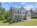 Two-story home featuring a welcoming covered front porch, attached garage, and neat landscaping at 99 Wildlife Bridge Ct, Spring Lake, NC 28390