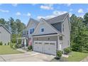 View of the home's exterior with an attached garage, well-kept lawn, and mature trees at 99 Wildlife Bridge Ct, Spring Lake, NC 28390
