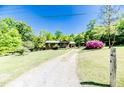Charming home exterior with a long driveway, lush green lawn, and blooming azalea bushes at 1409 Dogwood Acres Dr, Sanford, NC 27330
