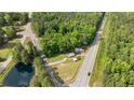 Aerial view showcasing the house and its proximity to a pond and surrounding trees at 3042 Overhills Rd, Bunnlevel, NC 28323