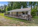 Side view of a house featuring a long covered porch with wood railing and steps at 3042 Overhills Rd, Bunnlevel, NC 28323