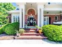 Charming front entrance with brick steps, lush landscaping, and a welcoming doorway at 4114 Chancellors Ridge Way, Sanford, NC 27330