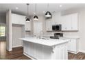 Bright kitchen features white cabinets, stainless steel appliances, a large island, and modern pendant lighting at 186 N Ashe Ave, Dunn, NC 28334