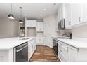 Open kitchen featuring white cabinets, stainless steel appliances, quartz countertops and sleek pendant lighting at 186 N Ashe Ave, Dunn, NC 28334
