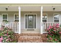 Inviting front porch with white columns, brick steps, and flowering bushes enhancing the home's curb appeal at 70 Mountainside Ln, Sanford, NC 27332