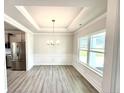 Elegant dining room with tray ceiling, wainscoting, wood-look floors, and a large window at 122 Southern Estates Dr, Sanford, NC 27330