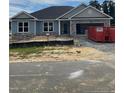 Single-story home featuring stone accents, garage door, and exterior undergoing construction with gravel and debris present at 21 Shoreline Dr, Lillington, NC 27546