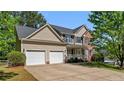 Traditional two-story home featuring a two-car garage, vinyl siding, brick accents, and a welcoming front porch at 227 Carolina Way, Sanford, NC 27332