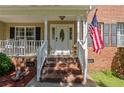 Inviting brick front porch with white columns, black shutters, and decorative front door with American flag at 227 Carolina Way, Sanford, NC 27332
