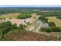 Expansive aerial view of the property showcasing a house, pond, and surrounding farmland and woods at 1445 Bethel Baptist Rd, Spring Lake, NC 28390