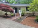 Charming home entrance with a brick walkway, mature landscaping, and a cozy front porch with white railings at 179A Fairway Ln, Sanford, NC 27332