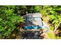 Aerial view of a light blue home with a dark roof and a spacious driveway surrounded by lush green trees at 416 Harbor Trce, Sanford, NC 27332