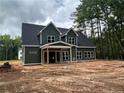 An exterior shot of a new home with green siding and white trim beneath a cloudy sky surrounded by tall trees at 194 Landon Rdg, Sanford, NC 27330