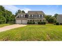 Inviting two-story home with a spacious lawn, attached two-car garage, and mature trees at 11 Checkmate Ct, Cameron, NC 28326