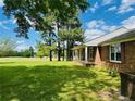 Spacious side yard with lush green grass, mature trees, and partial view of the brick home at 5163 Odell King Rd, Burlington, NC 27217