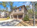 Exterior of home with stone facade and two-car garage featuring a long driveway and wooded surroundings at 76 Slate Dr, Spring Lake, NC 28390