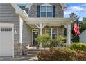 Close-up of home's charming covered front porch with stone pillars and lovely landscaping at 102 Scholar Dr, Spring Lake, NC 28390