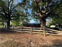 View of home behind a wooden fence and mature trees that accent the landscape and provide shade at 12558 Mcdougald Rd, Broadway, NC 27505