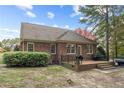 View of the brick back exterior with a small deck, patio, and mature landscaping at 35 Shining Water Ln, Spring Lake, NC 28390