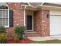 Close-up view of the brick front entrance with a dark front door and manicured landscaping at 35 Shining Water Ln, Spring Lake, NC 28390
