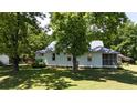 Exterior view of the white house showcasing its metal roof, screened porch, and well-kept lawn at 3997 Swanns Station Rd, Sanford, NC 27332