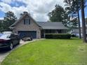 Home featuring a well manicured lawn, two-car garage, and covered front porch at 49 Pebble Beach Pt, Sanford, NC 27332
