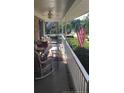 Inviting covered front porch featuring outdoor seating with decorative pillows, railing, and green landscaping at 49 Pebble Beach Pt, Sanford, NC 27332