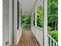 View of the front porch with its wood flooring, white columns and railings and wooded view at 635 Buckroe Dr, Sanford, NC 27330