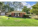 Ranch-style home featuring lush green lawn, brick accents, and a storage shed in the backyard at 3000 Currituck Dr, Sanford, NC 27332